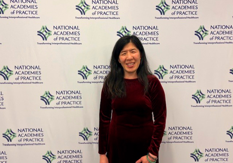 woman in front of backdrop with a repeated logo