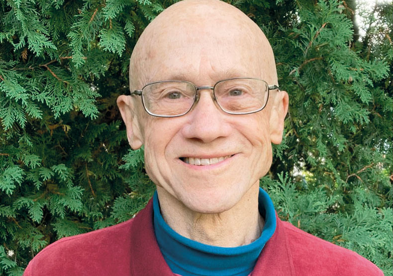 Photo of a man with trees behind him