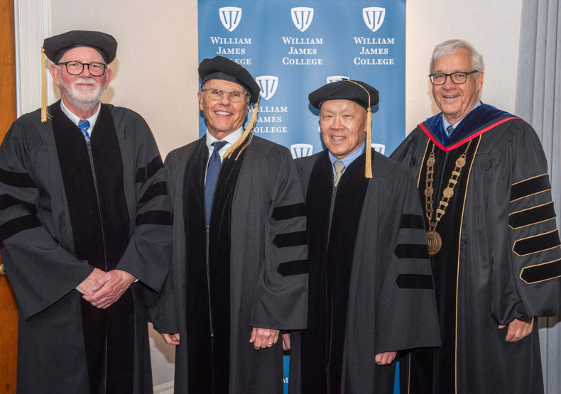 4 people standing together in graduation robes