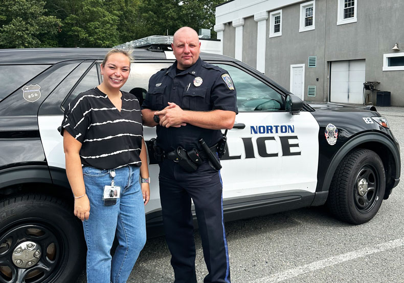 woman and police officer standing in front of a police car