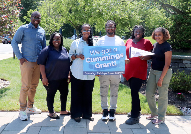 students and faculty standing with sign
