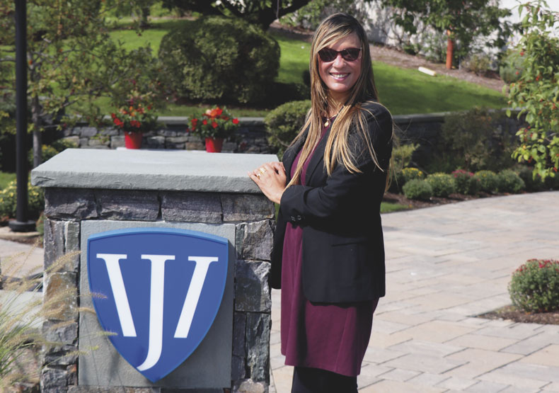 photo of woman smiling standing next to william james college sign