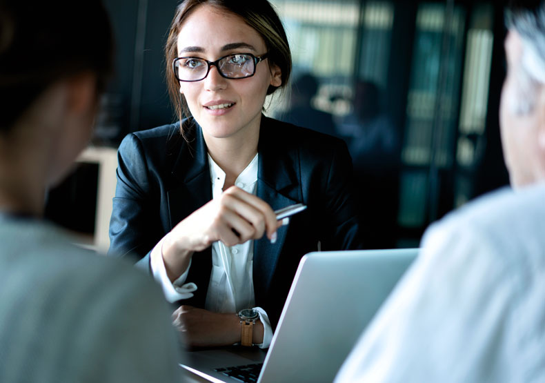 photo of woman sitting at table and talking with colleagues