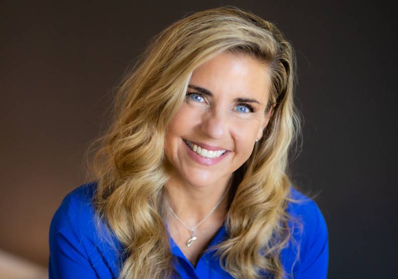 Picture of Janet Barrett smiling. She is wearing a blue dress and has blonde hair.