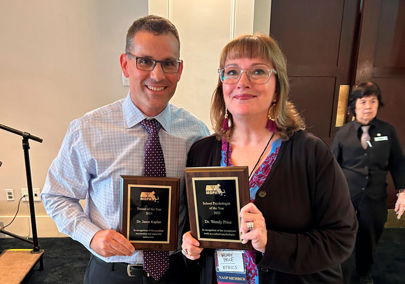 Man and woman holding awards and smiling