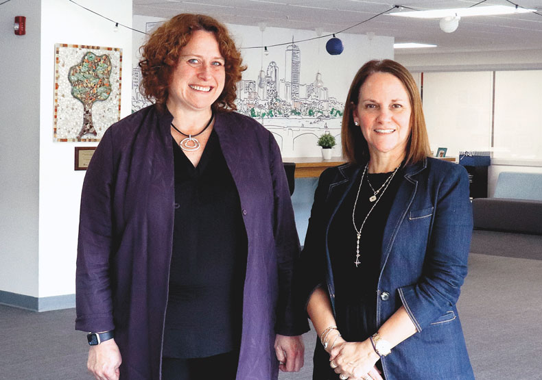 two woman standing in empty classroom and smiling 