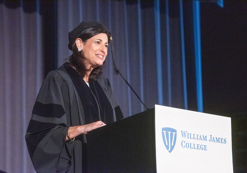 woman in cap and gown speaking at podium