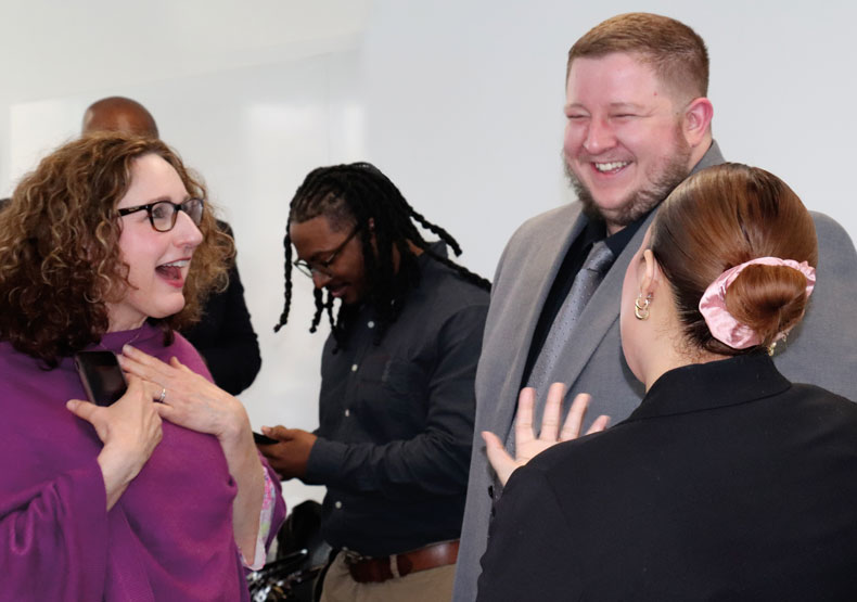 Ryan Duquette with Suzanne Devlin small group of adults talking and laughing in a classroom setting