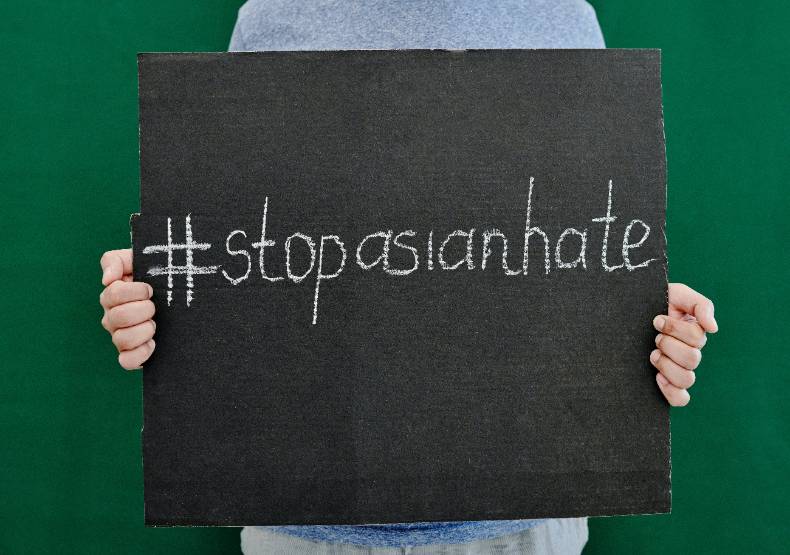 a picture of a person holding up a sign that says #stopasianhate