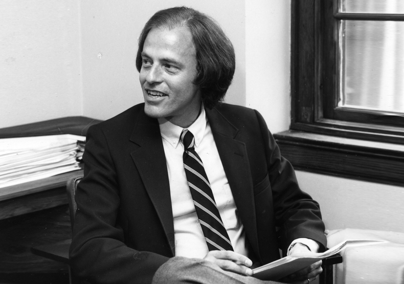 black and white photo of man sitting at desk looking to the left