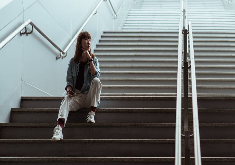 Woman sits on empty stairs.