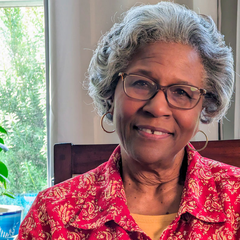 portrait photo of an elderly black woman wearing glasses and smiling