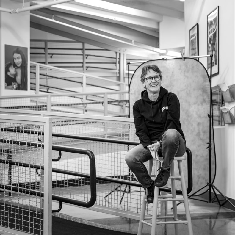 Black and white photo of woman sitting on a stool with a series of ramps behind her